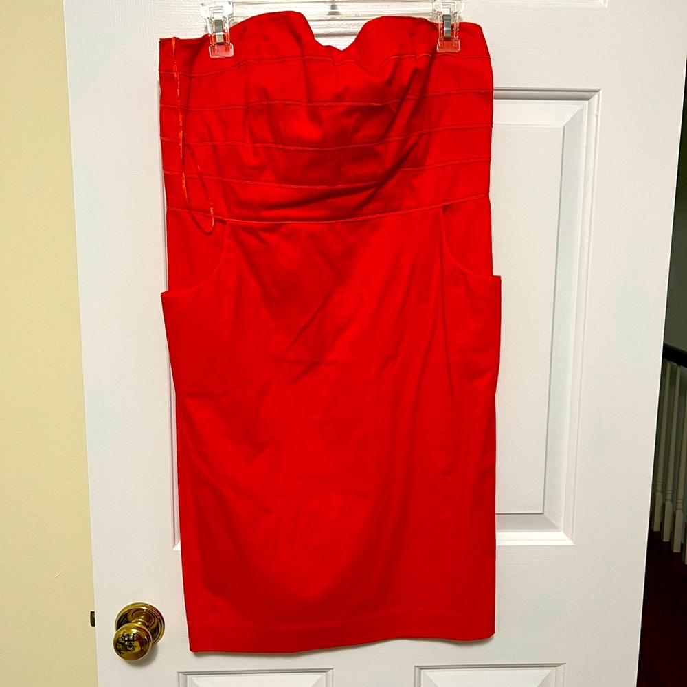 Coral colored strapless dress with piping detail across bust.